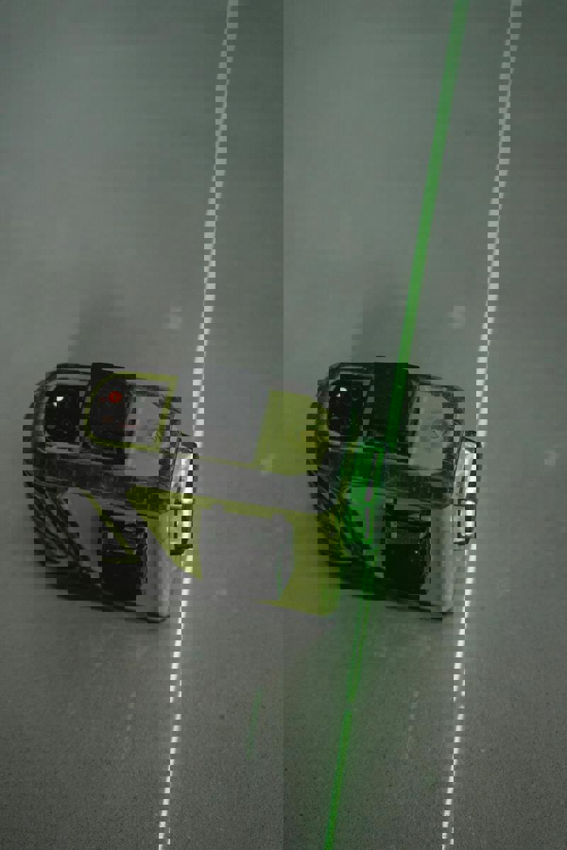Närbild på en laserpass med grön stråle som används för att skapa en rak och exakt linje vid bygg- eller renoveringsarbete.