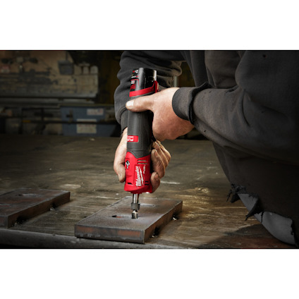 Person använder en röd och svart handhållen slipmaskin på metallplattor.