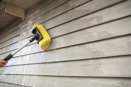 Gul borste på skaft används för att rengöra träfasad.