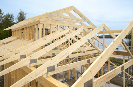 Trästomme av ett hus under konstruktion, med takbjälkar och himmel i bakgrunden.