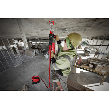 Person i skyddsutrustning använder en elektrisk borrmaskin på en byggarbetsplats.