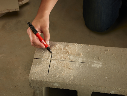 Hand ritar linjer på betongblock med röd penna.