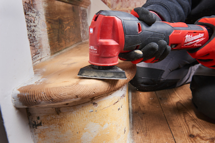 Person använder röd handhållen slipmaskin på en trappavsats.