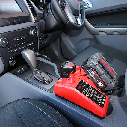 Bilinteriör med växelspak och en röd elektronisk enhet med svart etikett placerad i mittkonsolen.