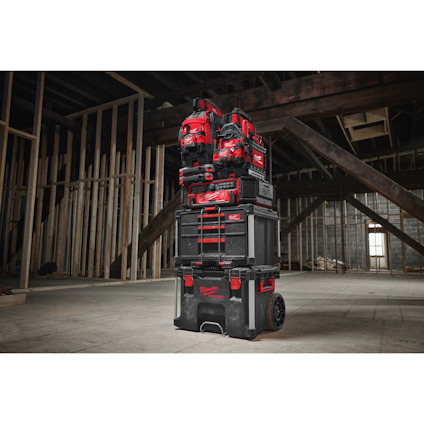 Röda och svarta verktygslådor staplade på varandra i en byggnad under uppbyggnad med synliga takbjälkar och väggstommar.