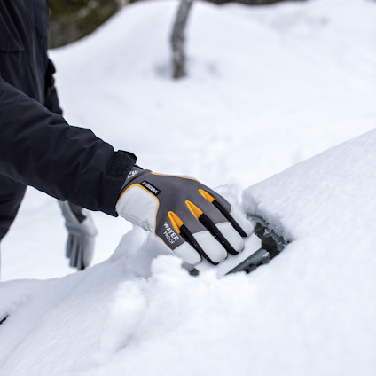 Person med handskar skrapar snö från en yta.