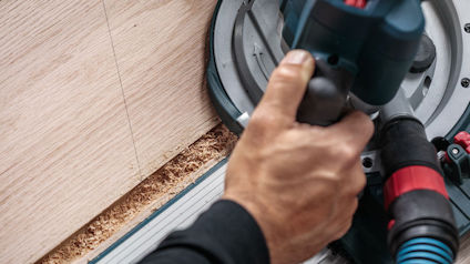 Hand som använder en cirkelsåg för att skära i trä.