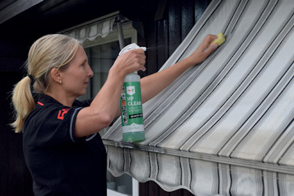 Kvinna rengör markis med sprayflaska och svamp.